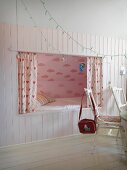 Romantic cubby bed with pink cloud-patterned wall in white wainscoting; rustic ambiance