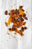 Pecan nut brittle on a white baking parchment (seen from above)
