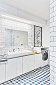 White, modern bathroom with tiled walls & floor, washstand with mirror, strip light & base units and washing machine fitted below shelf