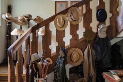 Hutsammlung an Holzgeländer und auf traditionellen Hutständern im Hintergrund