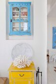 White coral on a yellow vintage box, light blue vintage display cabinets above in wall niche