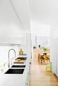 Open kitchen with white fitted wardrobes, view of dining table and chairs