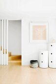 Bright, purist hallway with round containers next to foot of staircase