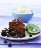 A slice of chocolate cake with berries and kiwi