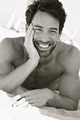 A young man laying on a beach supporting his head on his hand (black and white shot)