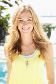 A blonde woman wearing a light yellow top and a fashionable necklace