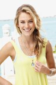 A blonde woman wearing a light yellow top and a fashionable necklace
