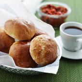 Breakfast rolls in a bread basket with a cup of coffee