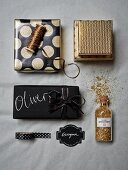 Christmas gifts wrapped in black and gold paper with matching ribbons arranged with gold glitter