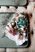 Olive-green tray of vintage-style Christmas decorations on upholstered surface