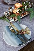 Festive place setting with name tag on floral tablecloth and tendril of foliage plant in foreground