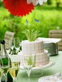 Two-tiered celebration cake and glasses of champagne outdoors