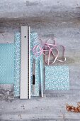 Patterned gift paper, ribbon, a ruler, a pencil and a craft knife