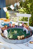 Stylised football pitch on metal tray with artificial grass and toy figurines as table decoration for football-themed party