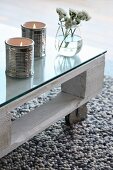 Ceramic tealight holders shaped like tin cans on coffee table made from white-painted wooden pallet, glass top and castors