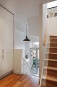 Stairwell with white wooden treads, runner and white fitted cupboard on landing