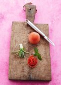 Selbstgemachte Gemüseblüten, Minzeblättchen und Tomate auf Holzschneidebrett