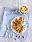 Chicken nuggets with garlic sauce, potato wedges and a courgette and pepper salad