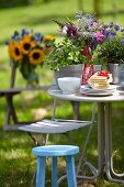 Blumenstrauss, Pflanztöpfe & Tellerstapel mit Waffeln auf Tisch im sommerlichen Garten