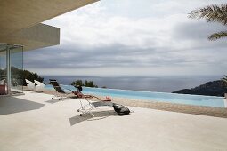 Puristisches Ambiente auf Sonnenterrasse mit Infinity-Pool und weitem Meerblick