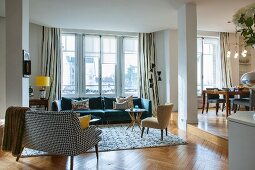 Fifties-style couch with black and white patterned cover and modern sofa below window in lounge area