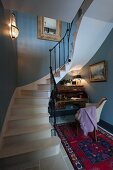 Writing desk, armchair and Oriental rug under curved staircase