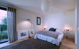 Frameless bed and two silver metal bedside tables in minimalist bedroom