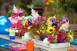 Bunte Becher mit sommerlichen Gartenblumen als Tischdeko