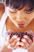 A woman smelling a handful of coffee beans