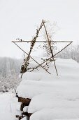 Star made from sticks on top of snow-covered woodpile