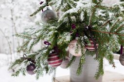 Weihnachtlich dekorierte Fichtenzweige mit Kugeln und Schleifen in altem Tongefäss