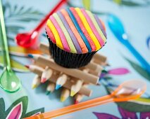 A cupcake decorated with coloured fondant stripes