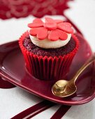 A red velvet cupcake decorated with red fondant flowers