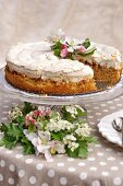 Apple cake with meringue top and fruit tree blossom on polka dot tablecloth outside