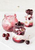 Three glasses of yoghurt muesli with cherry compote and cereals, one eaten