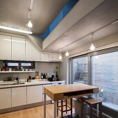 Fitted kitchen in South Korean house; sliding door leading to outdoor seating area with screen and slot in ceiling opening to upper storey