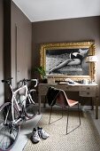 Racing bicycle next to desk below gilt-framed black and white photos