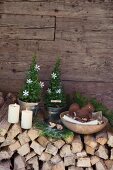 Hand-crafted felt squirrel in wooden bowl of nuts on festively decorated stack of firewood against cabin wall