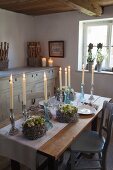Kerzenhalter und Kränze auf rustikalem Holztisch mit Tischläufer