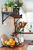 Wandbord mit Pflanzen über Küchenzeile mit Holzarbeitsplatte, Korb mit Orangen