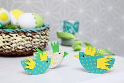 Easter arrangement in yellow and green; colourful, paper chicks as place cards