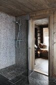 Bodenebene Dusche mit Mosaikfliesen, seitlich offene Tür mit Blick auf Bodenlaterne in Wohnraum