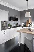 White, L-shaped kitchen counter below grey wall and stucco ceiling frieze with dining table and chairs in foreground