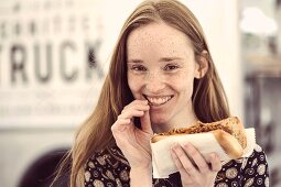 A young woman with a pulled pork sandwich