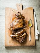 Sliced leg of lamb on a chopping board with a spoon