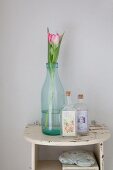 Tulpe in alter Milchflasche und Fläschchen mit nostalgischen Etiketten auf Vintage Wandbord