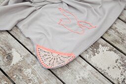 Pale grey picnic blanket with crocheted trim and seagull motif