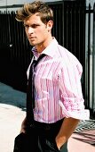 A young man wearing a pink and white striped shirt and black tie