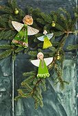 Paper angels with heads cut out of family photos hung on fir branch
