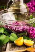Lilac flower syrup being made: flowers in a glass bowl with sugar syrup in the background